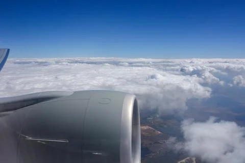 View of an airplane engine from a passenger window during flight above a layer o Stock Photos