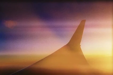 View of an airplane in flight during sunset, with the wing in the foreground Foto stock