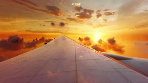 View of an airplane jet wing flying above sunset clouds orange sky Stock Footage 308995472