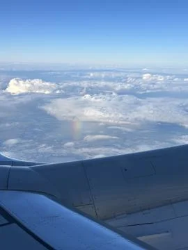 View from Airplane Window Above Clouds with Wing and Blue Sky Stock Photos