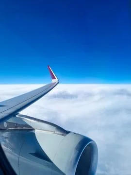 View from airplane window above dense white clouds with aircraft wing and engine Stock Photos