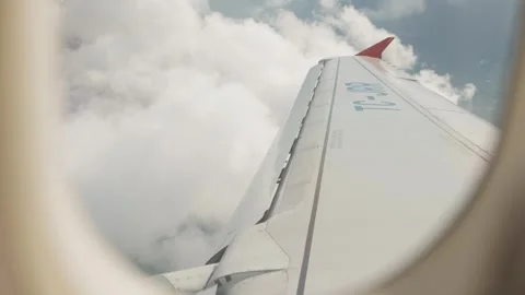View from Airplane Window as Aircraft Turns and Ground Appears Beyond Clouds Vídeos de archivo 346105570