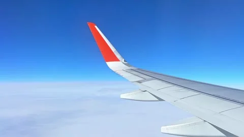 View from the airplane window at a beautiful cloudy sky and the airplane wing Stock Footage 305591900