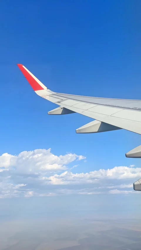 View from the airplane window at a beautiful cloudy sky and the airplane wing Stock Footage 305600162