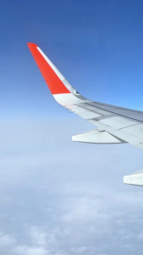 View from the airplane window at a beautiful cloudy sky and the airplane wing Stock Footage 305600251