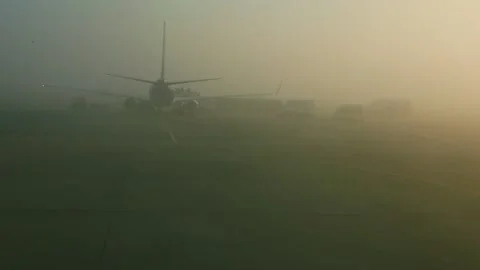 View from airplane window on big aircraft stands in fog on runway on sunrise Stock Footage 134569354