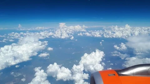 View from the airplane window to the blue sky and white clouds, an orange Stock Footage 92990661