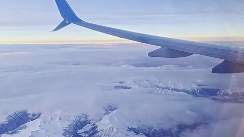 View from the airplane window to blue sky, clouds, mountains. 스톡 동영상 257992414
