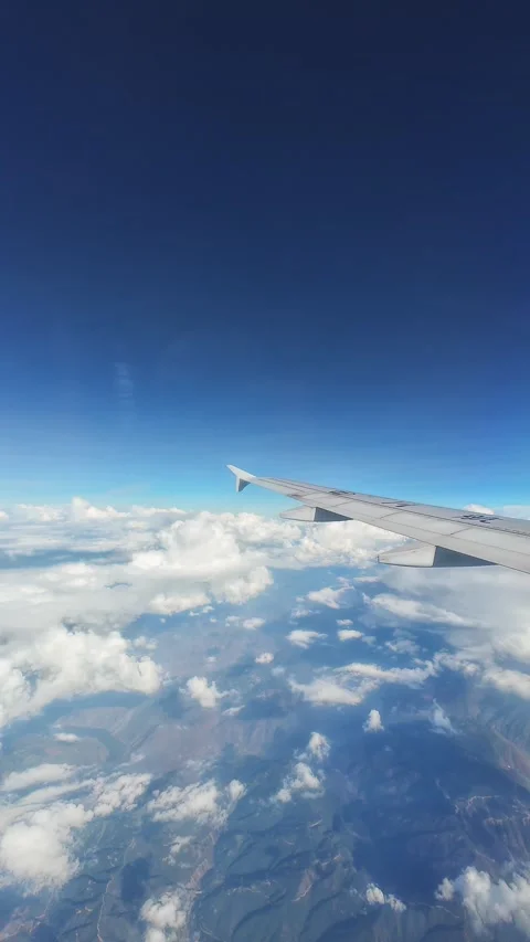 View from the airplane window at a blue sky with clouds and earth. Stock Footage 316479861