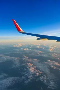 The view from the airplane window to the clouds and sunset. Airplane wing abo Stock Photos