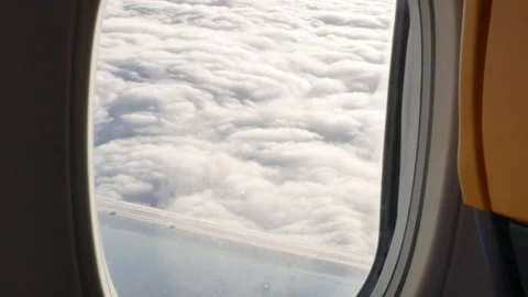 View from airplane window on clouds lit by the sun - 4K, Handheld Stock Footage 167434393