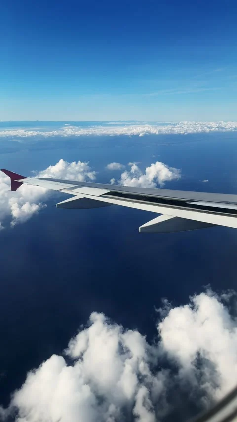 View from the airplane window to the clouds, the plane flies over the sea Stock Footage 303644735