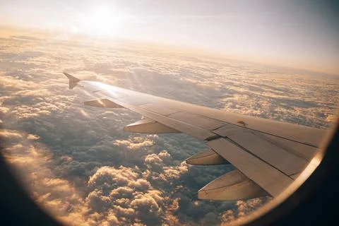 View from the airplane window to the clouds in the sky under the sun's rays Stock Photos