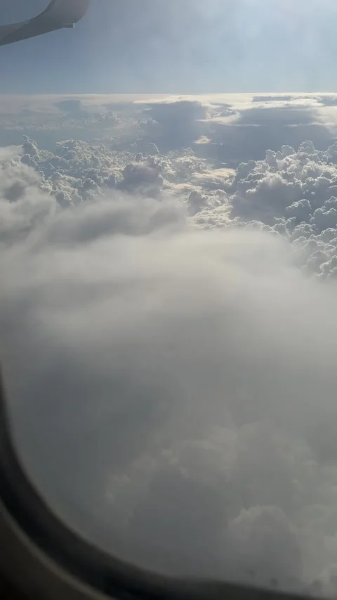 View from airplane window of dramatic clouds and clear blue sky during flight Stock Footage 297373563