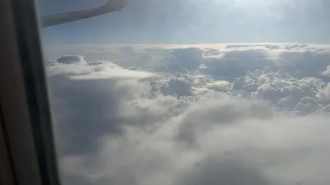 View from airplane window of dramatic clouds and clear blue sky during flight Stock Footage 297373579
