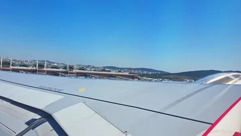 View from airplane window during takeoff with runway receding below and blu.. Video stock 338133369
