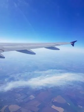 View from an airplane window featuring the aircraft wing soaring above scattered Stockfoto's