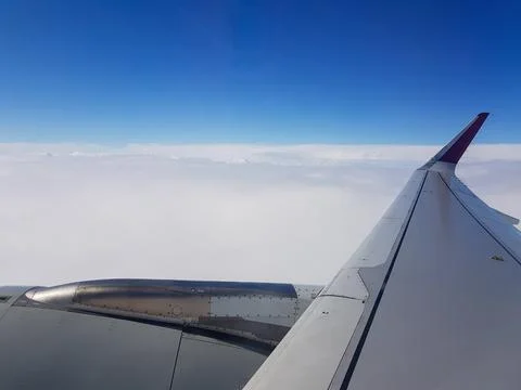 View from an airplane window featuring the aircraft wing and engine above a smoo Stock Photos