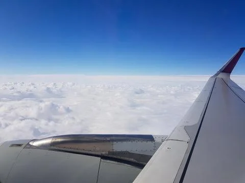 View from an airplane window featuring the aircraft wing and engine above a smoo 库存照片