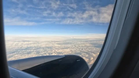 View from an airplane window featuring bright clouds and a clear blue sky Video stock 339070954