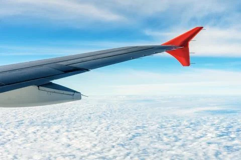 View from an airplane window featuring the wing against a backdrop of blue sky Stock Photos