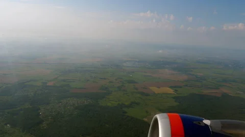 View from airplane window of green fields and forests below jet engine Stock Footage 346351971