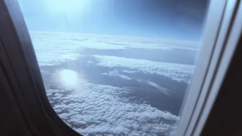 View from an airplane window of low clouds above the ground, camera tracking Stock Footage 247206868