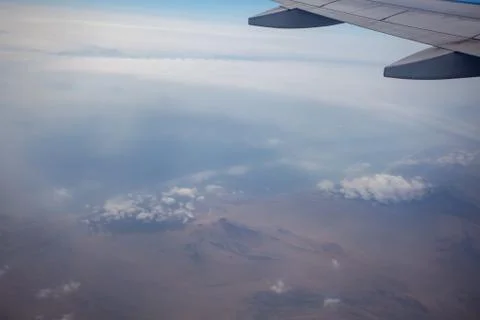 The view from the airplane window on the mountains in the clouds. Stock Photos