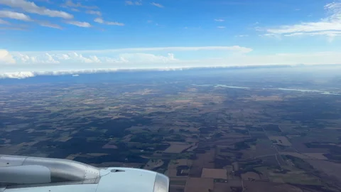 View from an airplane window over wing and a vast patchwork of farmland below Video stock 333794304