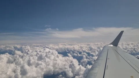 View from an airplane window overlooking endless soft white clouds, with the Stock Footage 346420953
