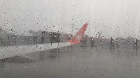 View from Airplane Window of Red Wing on a Rainy Day at Airport Tarmac Stock Footage 327247402