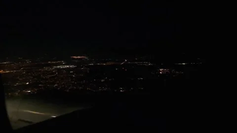 View from airplane window showing glowing city lights at night Stock Footage 310451506