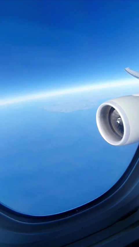 View from an airplane window showing a jet engine and wingtip above a blue sky a Stock Footage 336960497