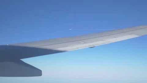 View from airplane window showing wing and clear sky in 4k Stock Footage 279663256