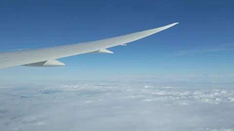 View from an airplane window showing the wing and clouds below in 4k slow m.. Stock Footage 283080801