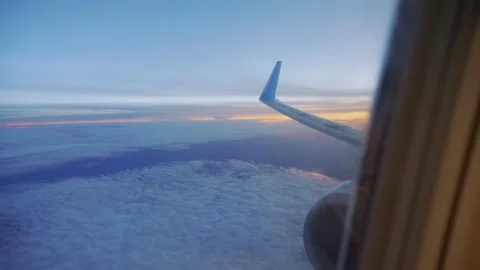 A view from an airplane window showing the wing and clouds at sunset in 4k .. Stock Footage 285122673