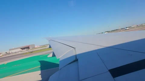 View from airplane window showing wing and airport runway below Stock Footage 288123648