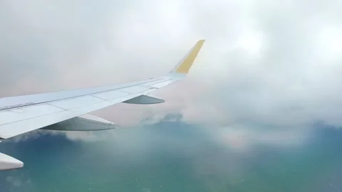 View from an airplane window showing the wing flying over the sea with white Vidéo 332771949