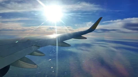 View from airplane window showing wing above clouds with sunlight and Vidéo 332792687