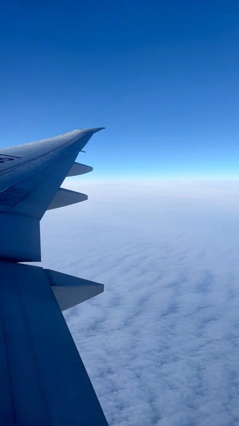 View From Airplane Window Showing Wing Above Clouds Under Blue Sky in Russia Stock Footage 346281262