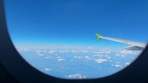 View from airplane window showing wing above clouds under clear blue sky. Aerial Stock Footage 346688669
