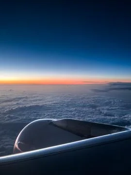 View from an airplane window showing the wing above a sea of clouds at sunr.. 写真素材