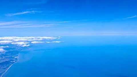 View from airplane window with soft blue sky and travel above the clouds Stock Photos