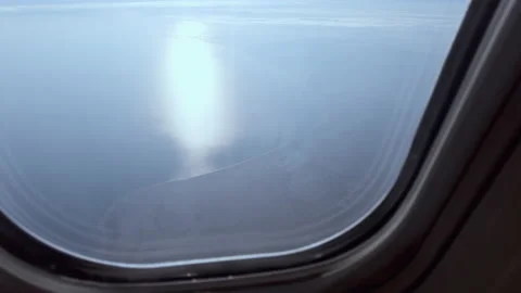 View from an airplane window, sun reflected in the water, land Stock Footage 230449097