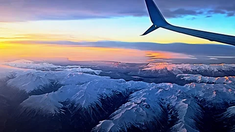 View from the airplane window to sunset, clouds, mountains. Video stock 258353582