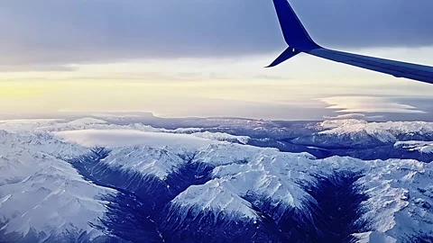 View from the airplane window to sunset, clouds, mountains. Video stock 258820450