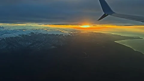 View from the airplane window to sunset, clouds, mountains. Video stock 258893725