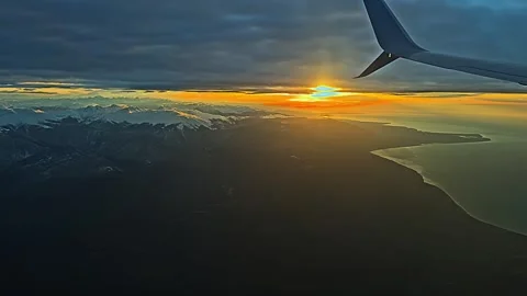 View from the airplane window to sunset, clouds, mountains. Stock Footage 260384445
