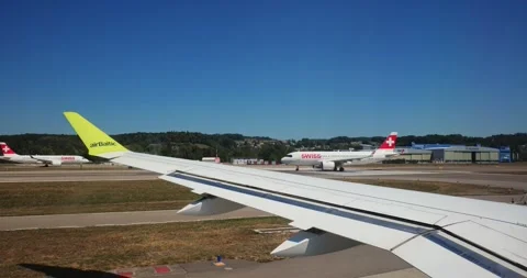 View from airplane window taxiing behind planes on runway during day. 스톡 동영상 346593666
