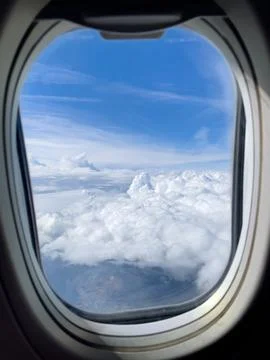 View from the airplane window to the white clouds and blue sky Stock Photos